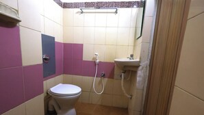 A small bathroom with a toilet, a sink, and a shower. - Amman Cottage (Perundurai)