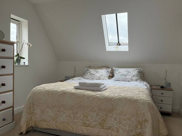 Un dormitorio con cama, cómoda, mesita de noche y ventana.