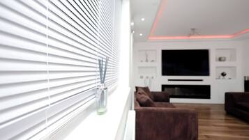 A modern living room with a large flat-screen TV, a brown sofa, and a white radiator.