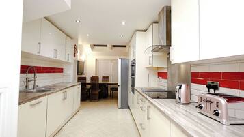 A modern kitchen with white cabinets, a stainless steel refrigerator, and a toaster.