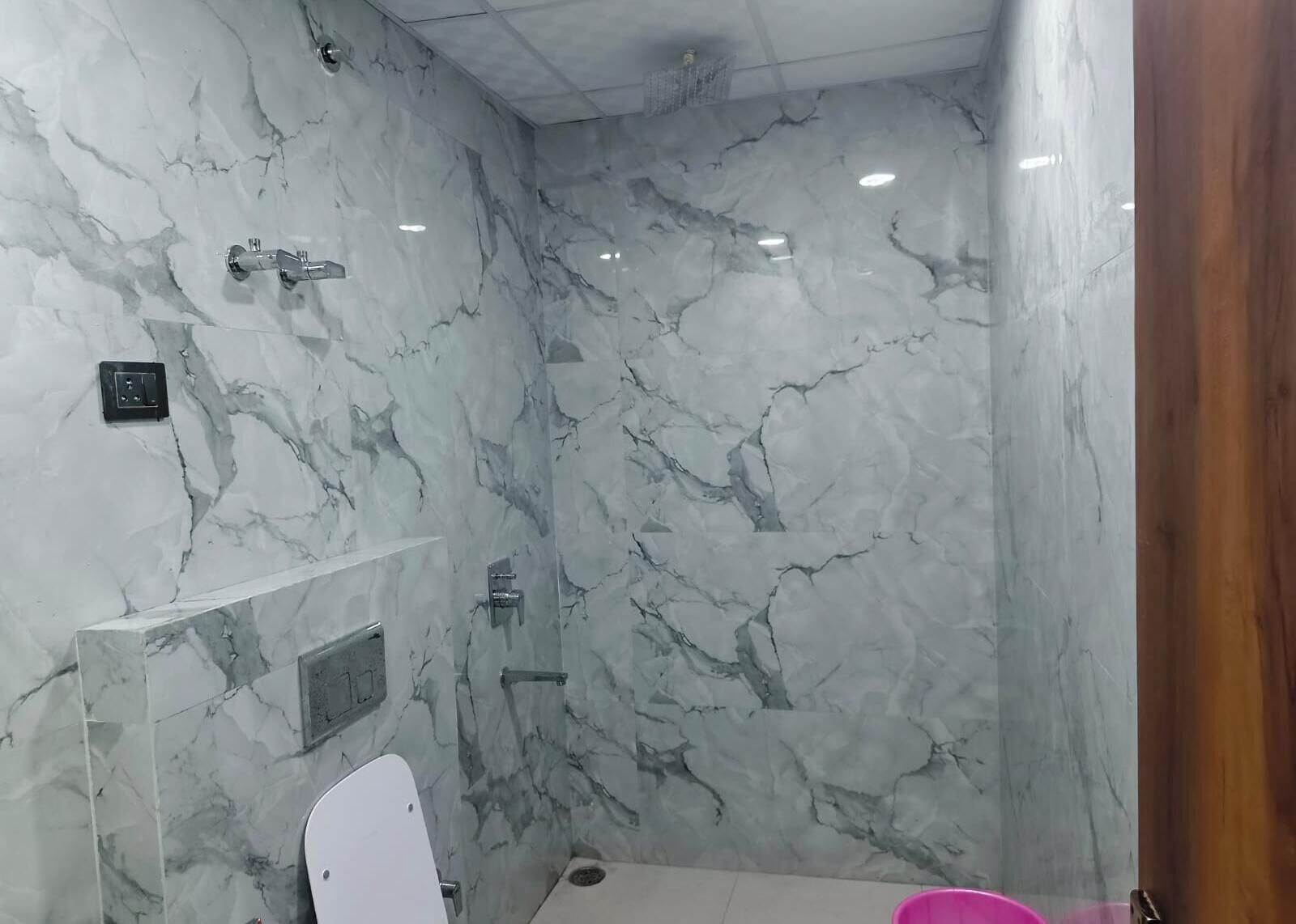 Une salle de bain avec des murs en marbre et un espace douche.