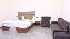 A bedroom with a bed, a nightstand, a chair, and a sofa.