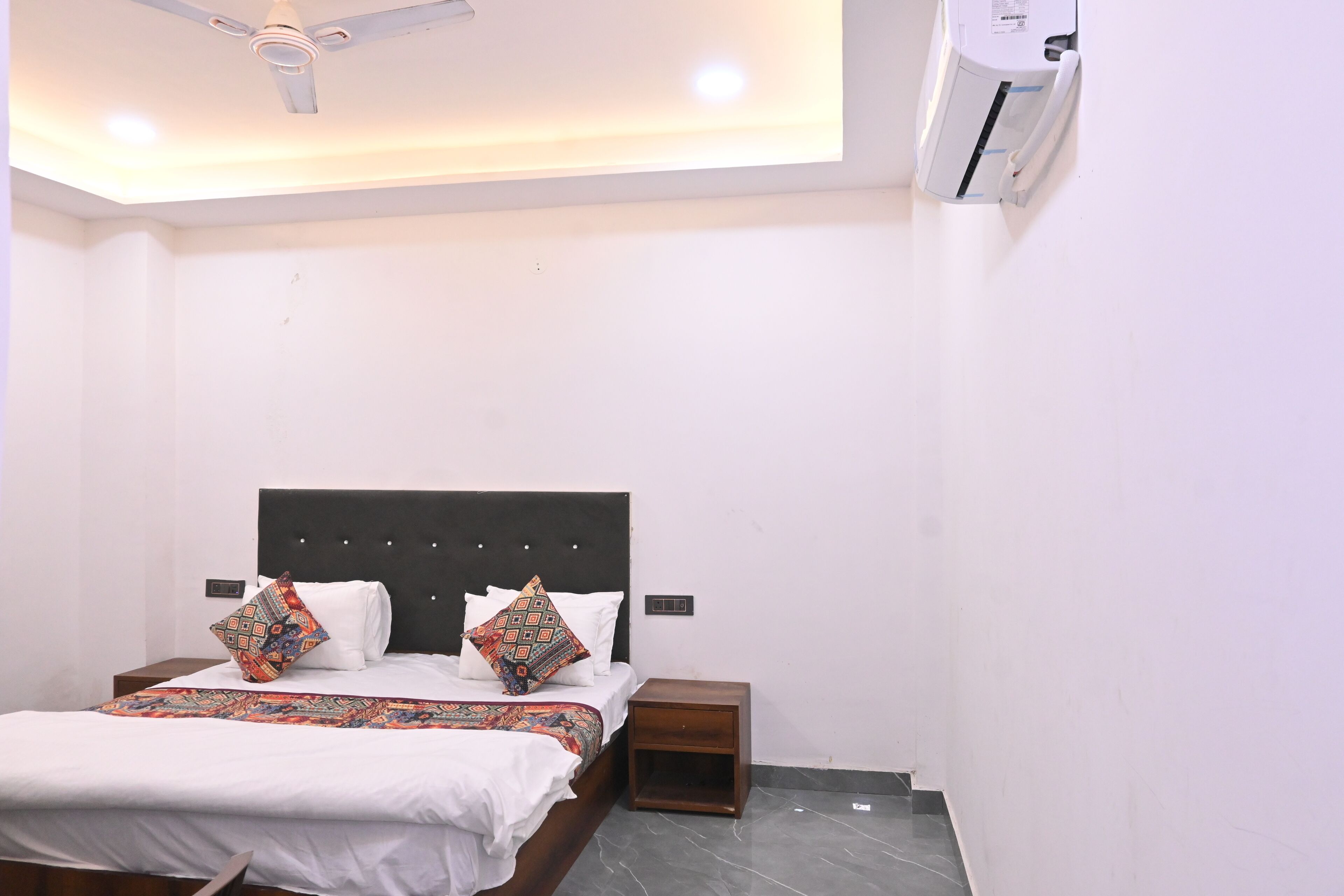 A neatly arranged bedroom with a bed, bedside tables, a ceiling fan, and an air conditioning unit.