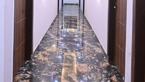 A long, narrow hallway with a polished marble floor, recessed ceiling lighting, and doors on both sides.