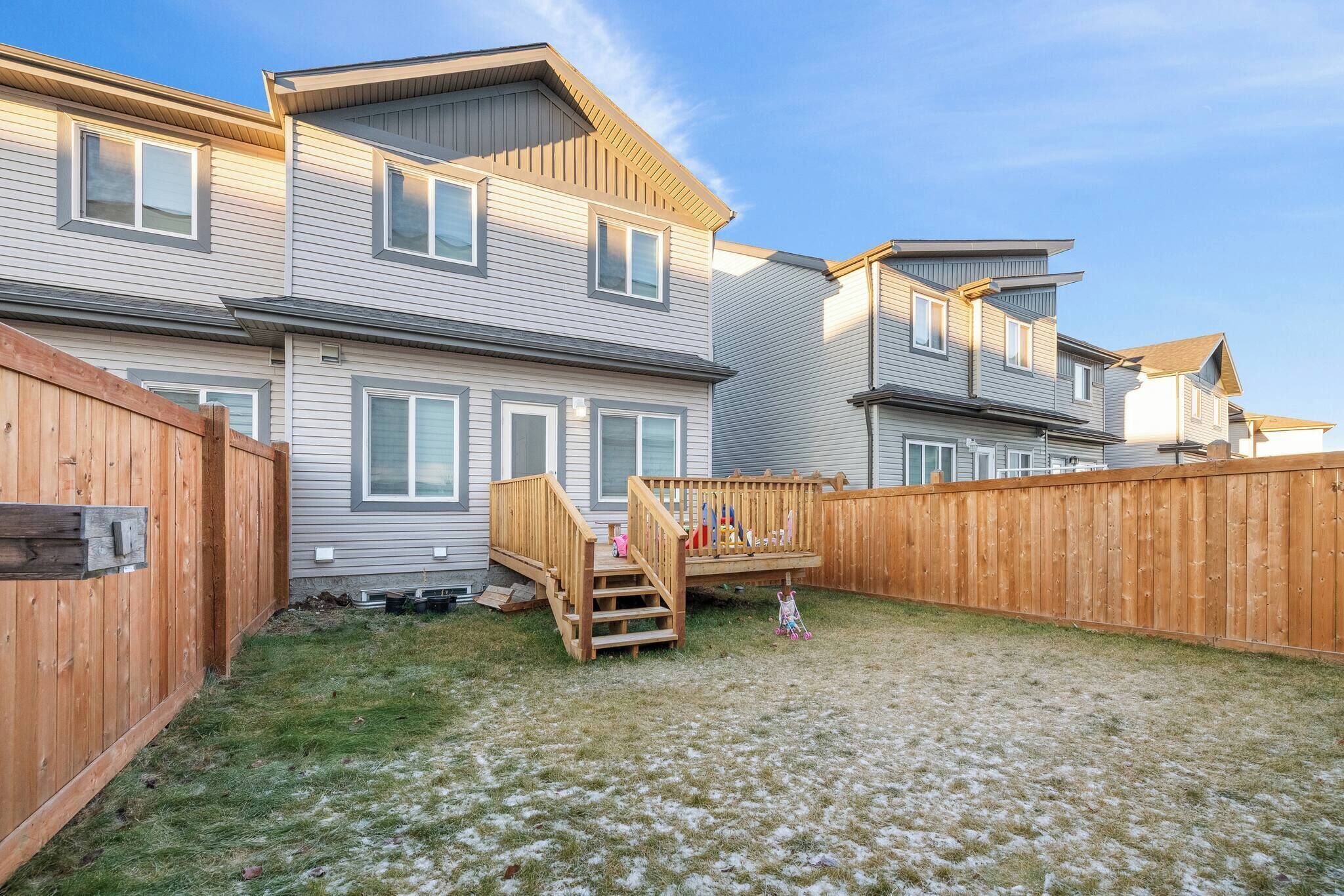 Zona residencial con varias casas, una terraza de madera y un patio cubierto de césped.