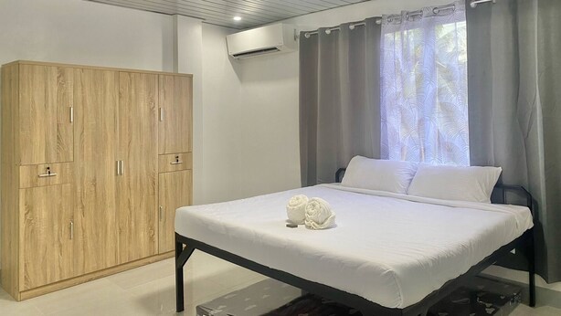 Quarto com uma cama, guarda-roupa e janela com cortinas.