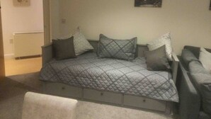 Ein Schlafzimmer mit Bett, Stuhl, Heizkörper und einem Bild an der Wand.