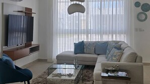 Una sala de estar moderna con sofá, mesa de centro y televisor.