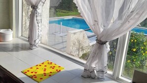 A kitchen with a view of a swimming pool, a yellow mat with red cherries, and a gas stove. - Discover the colonial jewel in Villeta-Cundinamarc (Villeta)