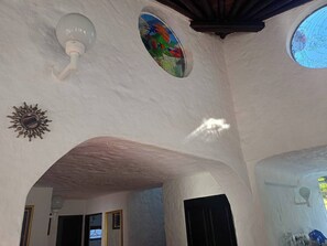 A room with a high, vaulted ceiling, a decorative sunburst, a stained glass window, and a skylight.