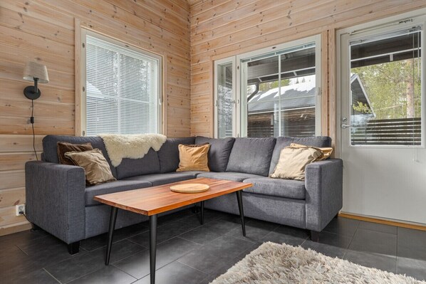 Ein modernes Wohnzimmer mit einem grauen Sofa, einem Holztisch und einem flauschigen Teppich.
