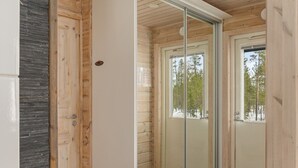 Un intérieur moderne avec une porte-fenêtre coulissante donnant sur un balcon, des murs en bois et un revêtement de sol en carreaux de couleur sombre.