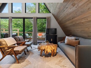 Ein modernes Wohnzimmer mit großem Fenster, Holzboden und einem Flachbildfernseher.