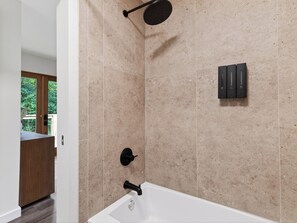 A modern bathroom with a bathtub, a showerhead, and a toilet. - A-Frame Cabin • Hot Tub + Sauna • Near Pigeon Forge | Fireside on Mortar (Sevierville)