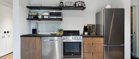 Una cocina moderna con electrodomésticos de acero inoxidable, armarios de madera y un horno empotrado.