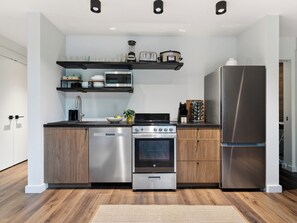 A modern kitchen with stainless steel appliances, wooden cabinets, and a built-in oven. - A-Frame Cabin • Hot Tub + Sauna • Near Pigeon Forge | Fireside on Mortar (Sevierville)