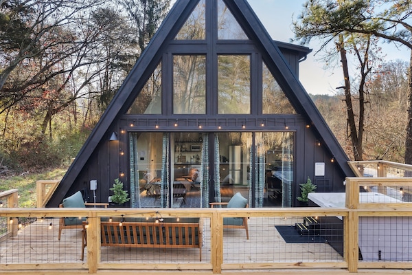 Striking A-frame in the trees with a spacious deck, string lights, and a private hot tub for post-adventure soaks.