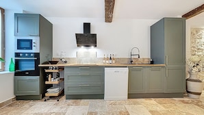 A modern kitchen with built-in appliances, a dishwasher, and a stone backsplash.
