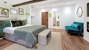 A bedroom with a bed, bench, and teal sofa.