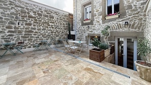 A stone building with a courtyard, outdoor seating, and potted plants.