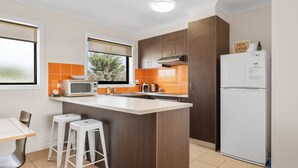 A modern kitchen with a central island, white appliances, and orange backsplash tiles. - Oceanic Stay in central Cowes (Cowes)