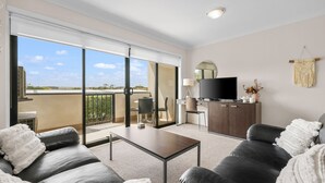 A modern living room with a sofa, a coffee table, a TV, and a balcony with a view. - Oceanic Stay in central Cowes (Cowes)
