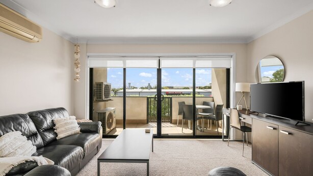 A modern living room with a leather sofa, a flat-screen TV, and a dining area with chairs and a table. - Oceanic Stay in central Cowes (Cowes)
