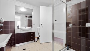 A modern bathroom with a white sink, dark wooden cabinets, a glass shower enclosure, and a large mirror. - Oceanic Stay in central Cowes (Cowes)