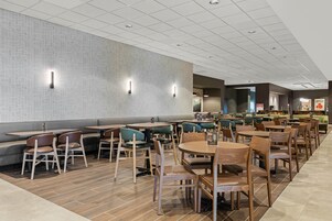 Un restaurante moderno con diversas opciones de asientos, incluyendo cabinas, mesas y sillas.