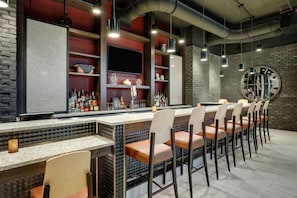 A bar area with a long counter, multiple shelves with bottles, and a large wall clock. - Drury Plaza Hotel Nashville Southeast Century Farms (Antioch)