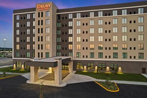 Un hotel Drury Plaza de varios pisos con techo plano, entrada cubierta y jardín ajardinado en la parte delantera.