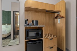 Una kitchenette compacta con microondas, cafetera y refrigerador pequeño.