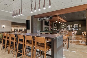 Un restaurante moderno con barra, sillas de madera y piso de baldosas.