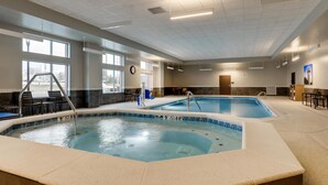 Una piscina interior con borde de azulejos, tragaluz y vistas al exterior.