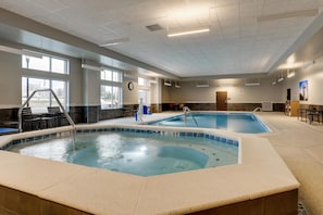 En indendørs swimmingpool med flisekant, ovenlys og udsigt til det fri.