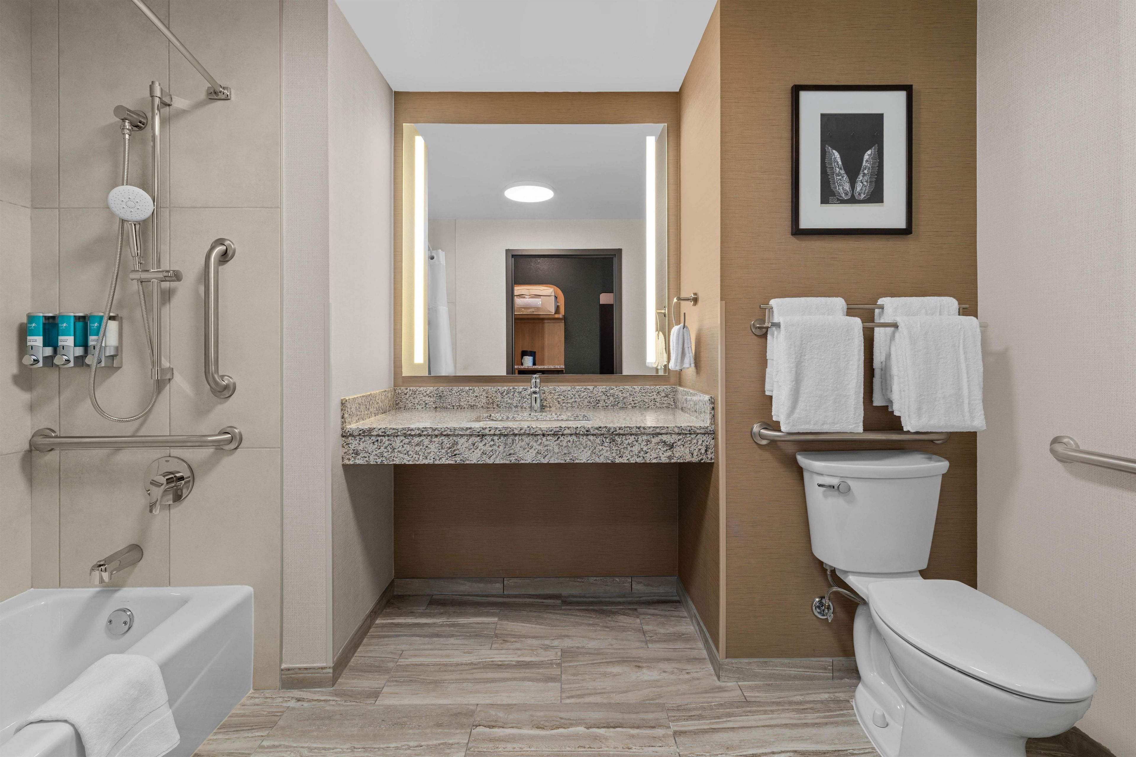 A modern bathroom with a shower, toilet, and sink.