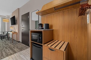 Una kitchenette compacta equipada con microondas, cafetera y un refrigerador pequeño.