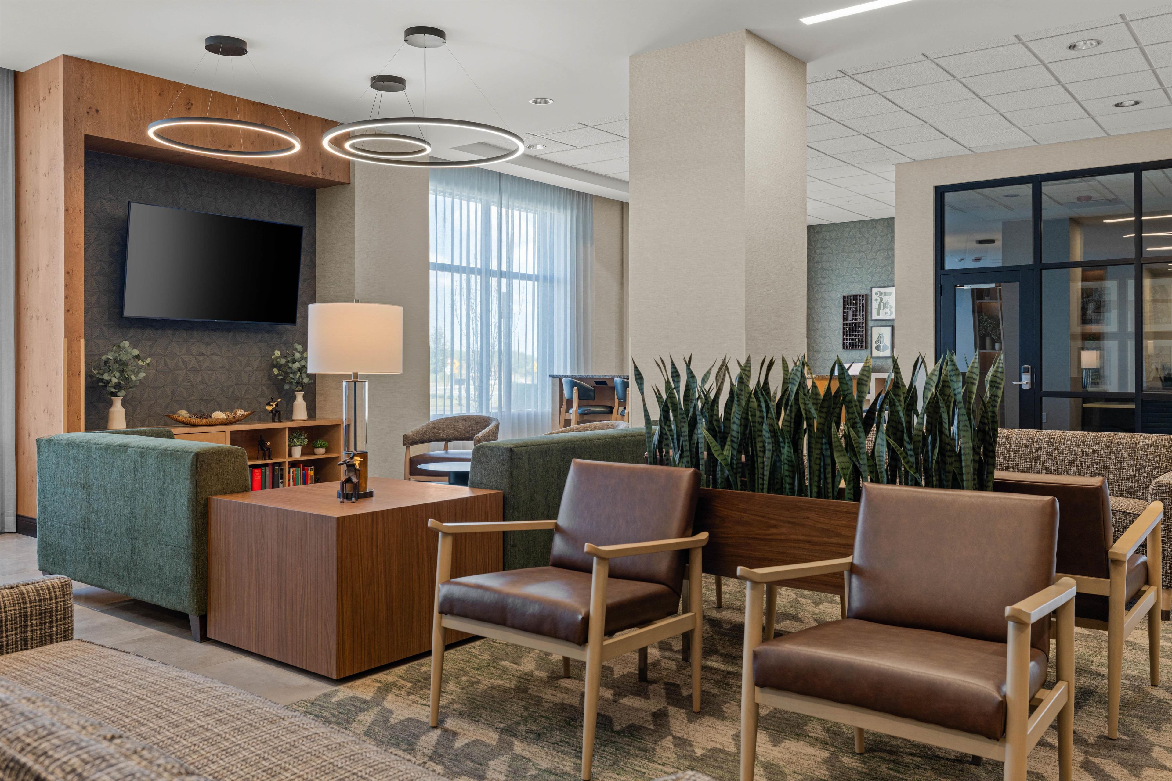 A modern lobby with a reception desk, seating area, and a large window.