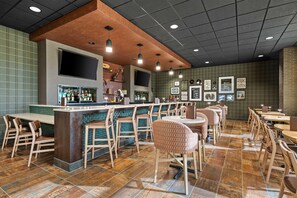 A bar area with a counter, stools, and a seating area with tables and chairs. - Drury Plaza Hotel Nashville Southeast Century Farms (Antioch)