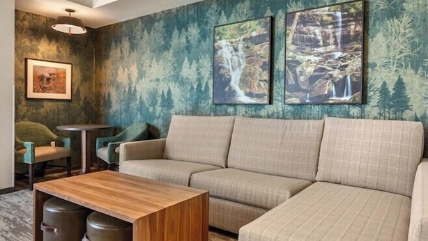 Una sala moderna con un sofá seccional, una mesa de centro de madera y dos cuadros con imágenes de cascadas.