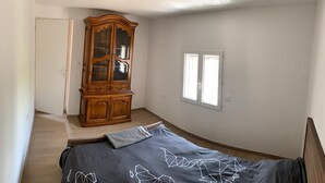 Een slaapkamer met een bed, een houten kast, een raam en een deur.