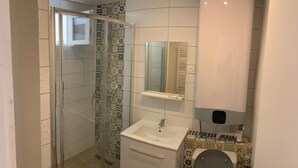 Een badkamer met een douchecabine van glas, een wastafel met spiegel erboven en een toilet.