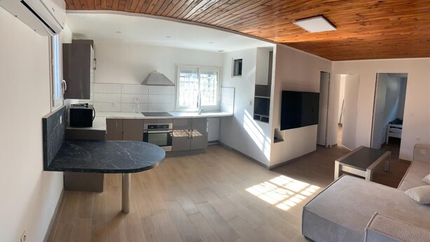 Een compacte keuken met moderne apparatuur, een eethoek met een marmeren tafel en een gezellige zithoek met een bank en een televisie.