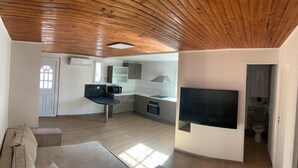 Een moderne keuken met een ingebouwde televisie, een zithoek met een bank en een houten plafond.