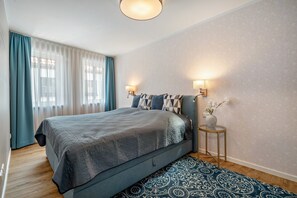 A bedroom with a bed, curtains, a bedside table, and a wall-mounted lamp. - Apartment "Seeblick" with Lake View, Shared Terrace and Wi-Fi (Malchow)