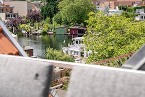 A canal with boats, a small dock, and buildings with red roofs.