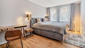 A bedroom with a bed, a desk, a chair, and a window with curtains. - Apartment "Seeterrasse" with Lake View, Shared Terrace and Wi-Fi (Malchow)