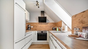 A modern kitchen with white cabinetry, a wooden countertop, and a built-in oven. - Apartment "Seeterrasse" with Lake View, Shared Terrace and Wi-Fi (Malchow)