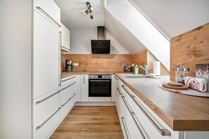 A modern kitchen with white cabinetry, a wooden countertop, and a built-in oven.
