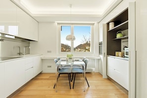 A modern kitchen with a dining table, white cabinets, and a window with a view of the outdoors. - Generoso Luxury Lake View Suite in Lugano (Lugano)